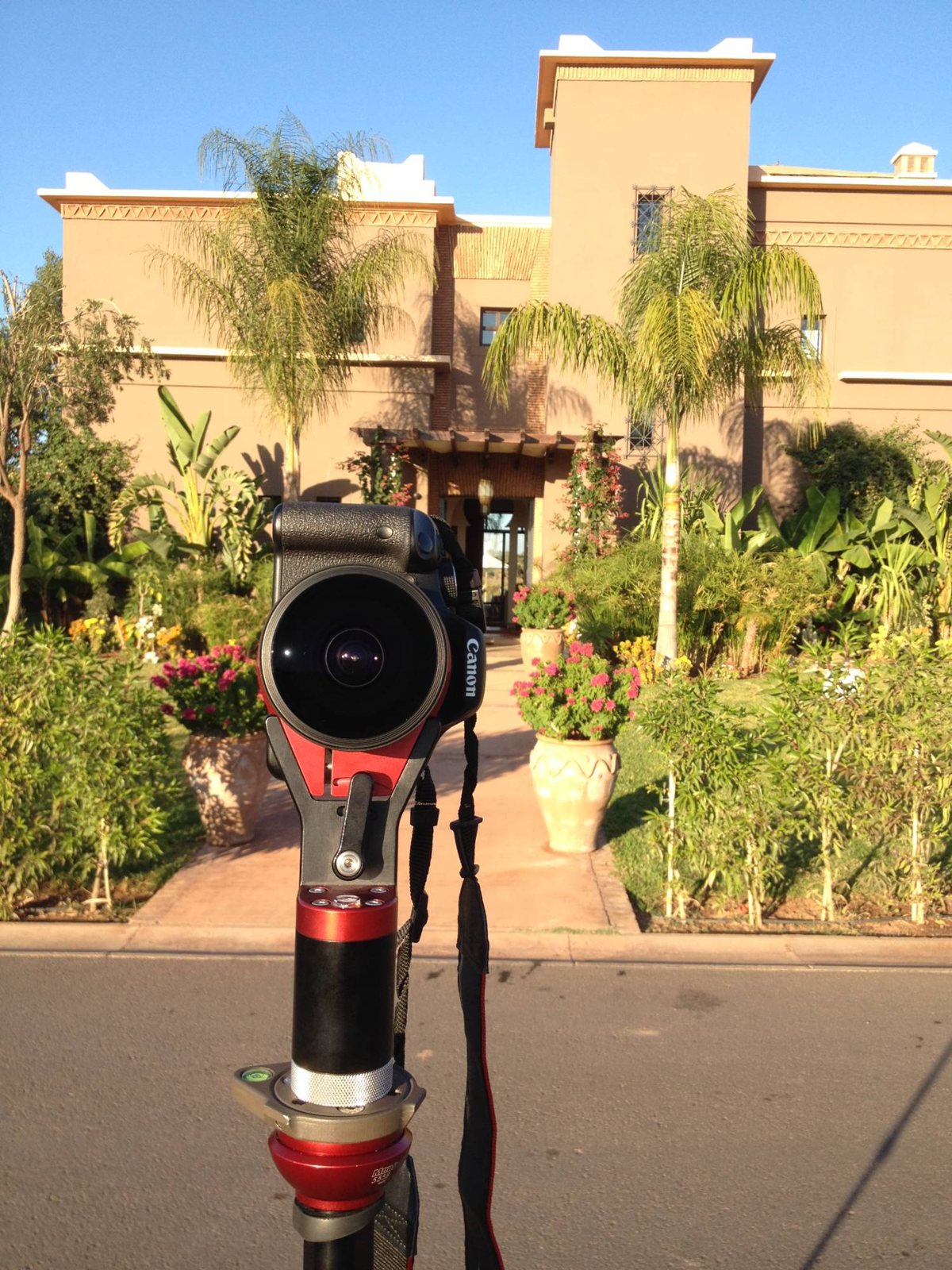 A Canon DSLR with a fisheye lens on a panoramic head outside a villa